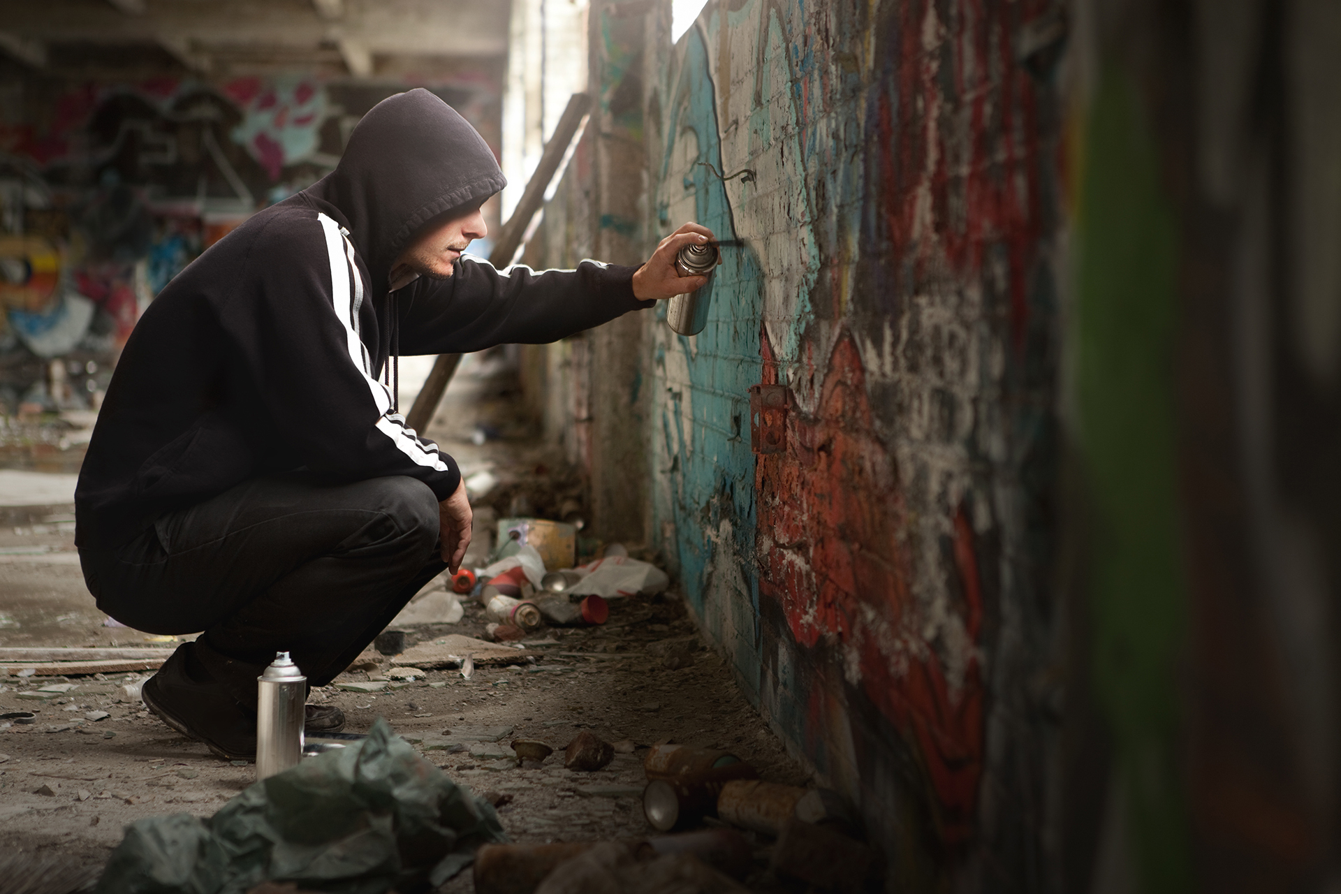 young man in hoodie spraying graffitti